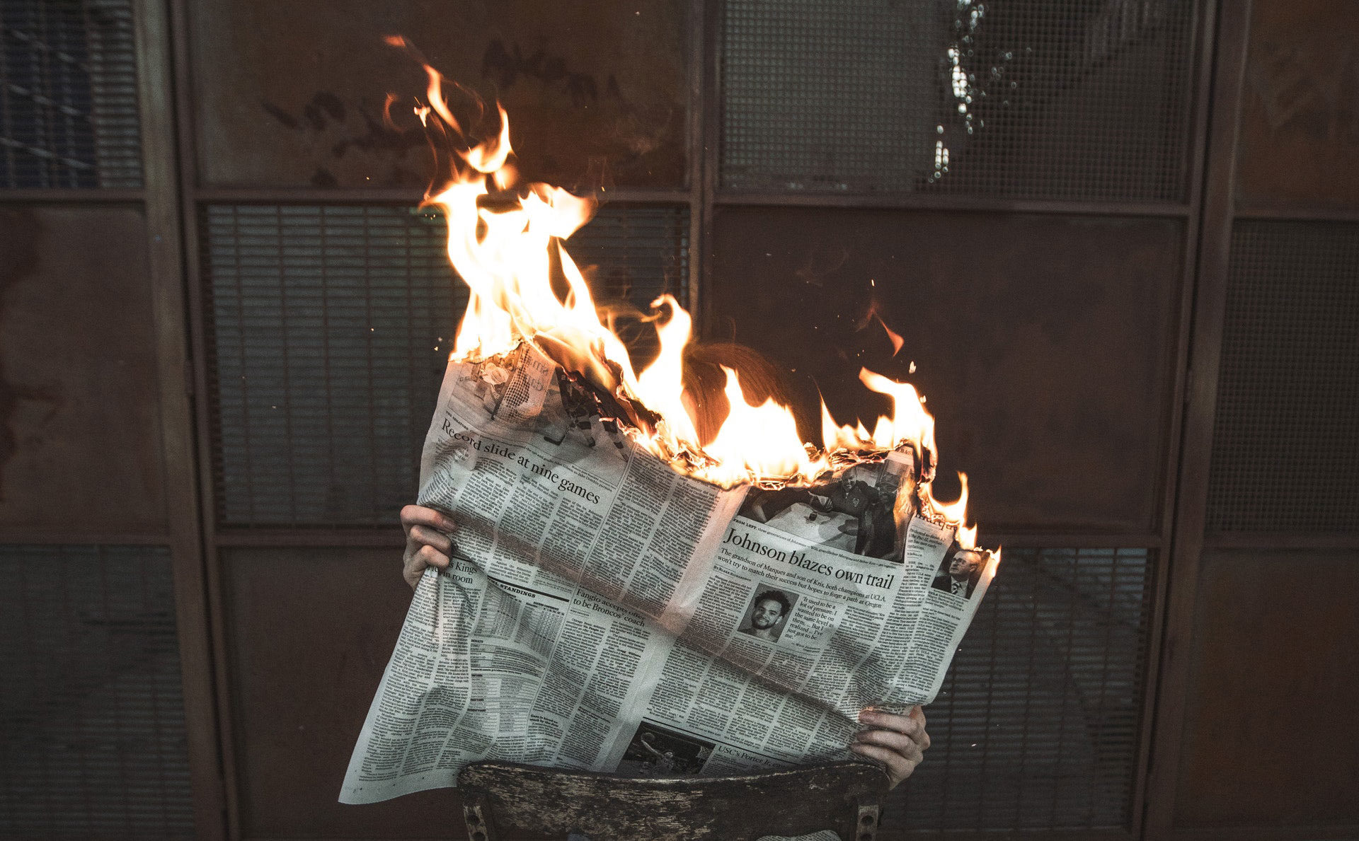 Man holding burning newspaper